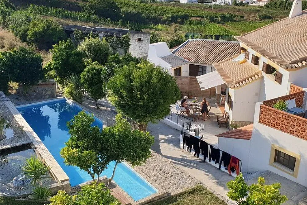 Far End Surf House — The retreat unfolds in a private villa nestled within the rolling hills of Portugal's picturesque coastline. Surrounded by 3,000 sqm of lush gardens, the atmosphere is one of natural tranquility and spaciousness, offering ample room to relax and enjoy the peaceful surroundings.
