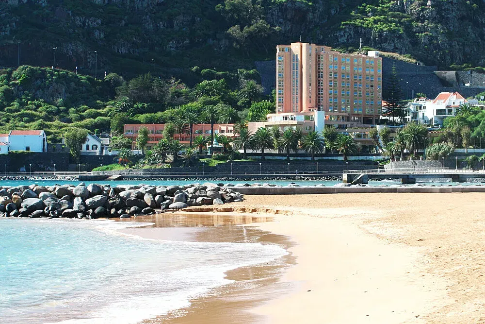 Hotel Dom Pedro Baía Machico — The hotel is situated directly on the shores of Machico Bay, providing immediate access to the beach and stunning ocean views. The atmosphere is described as peaceful and relaxed, with the natural beauty of the coastline creating a serene environment for guests.