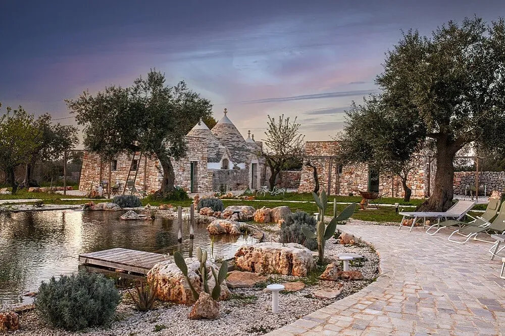 il fiore della vita — The retreat is set amidst the rustic beauty of the Italian countryside, with accommodations thoughtfully integrated into the natural landscape. The presence of ancient structures like trulli and renovated ruins suggests a setting steeped in history and local character, providing a peaceful and authentic atmosphere for reflection.