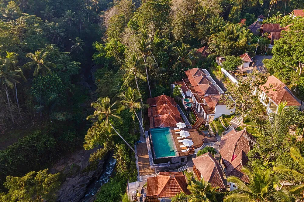 Kayuan Lumbur Resort — The resort is situated directly along the Campuhan River in Ubud, offering a deeply immersive natural environment. The atmosphere is one of serene tropical beauty, with lush greenery and the soothing sounds of the river creating a peaceful backdrop for relaxation.
