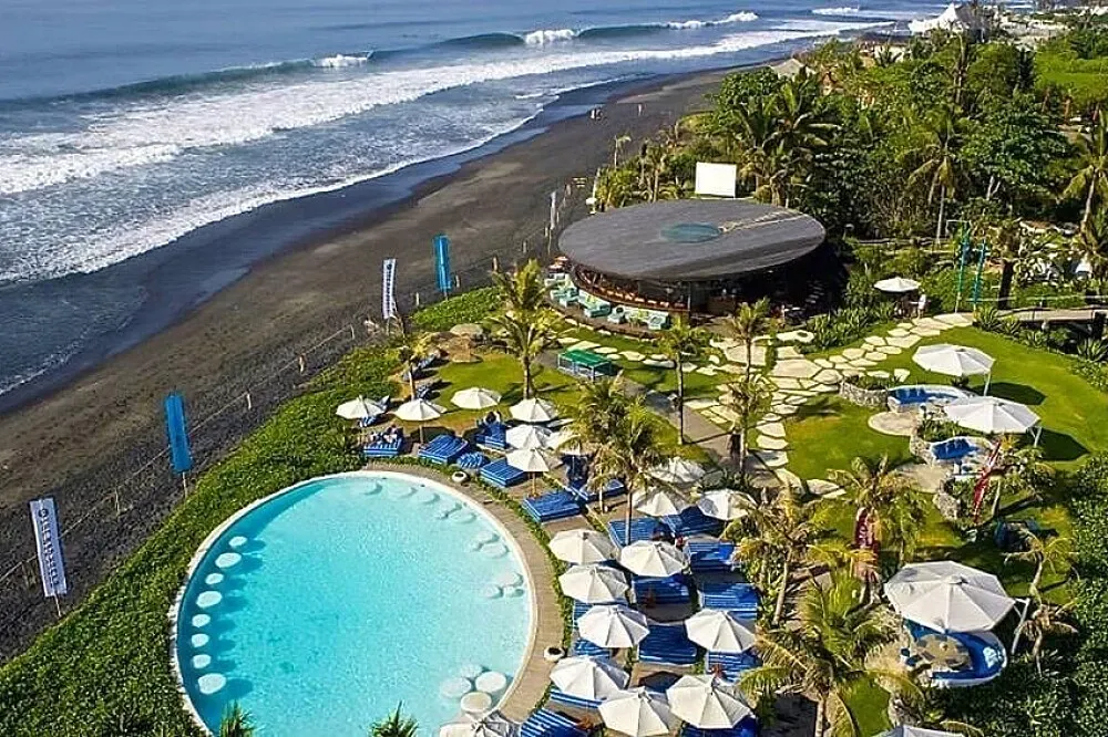 Komune Bali — set directly on Bali's Keramas Beach, the center boasts a unique landscape of stunning black sand and crystal-clear waters. The surrounding area is characterized by lush tropical greenery, creating a tranquil atmosphere that perfectly balances the vibrant energy of the ocean.