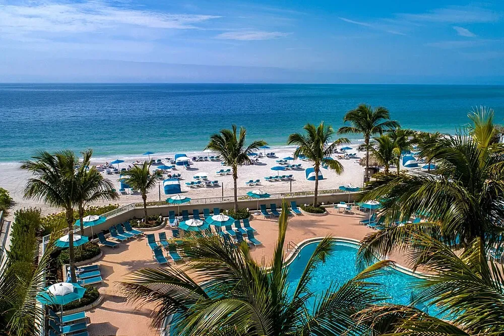 Lido Beach Resort — The resort is set directly on the white, powdery sands of Lido Key, offering an exclusive and secluded beach experience. The atmosphere is one of relaxed luxury, with the sounds of the ocean and the warmth of the Florida sun defining the environment. It's a place where the natural beauty of the coastline meets upscale resort amenities.