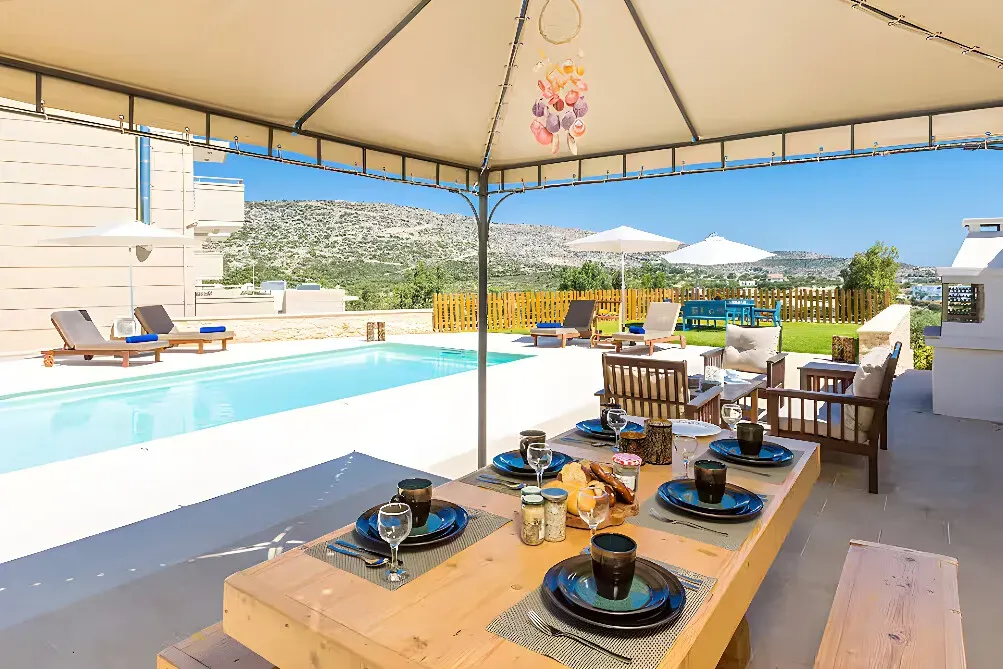 Loutraki Villas — Set amid rolling hills, Loutraki Villas are situated in a privileged location on the Akrotiri peninsula, Chania. The villas are only 150 meters from Loutraki beach, offering direct access to the clear waters and sandy shores of the Aegean Sea. The landscape combines lush greenery with the stark beauty of the coastline, providing a peaceful and inspiring atmosphere for personal reflection.