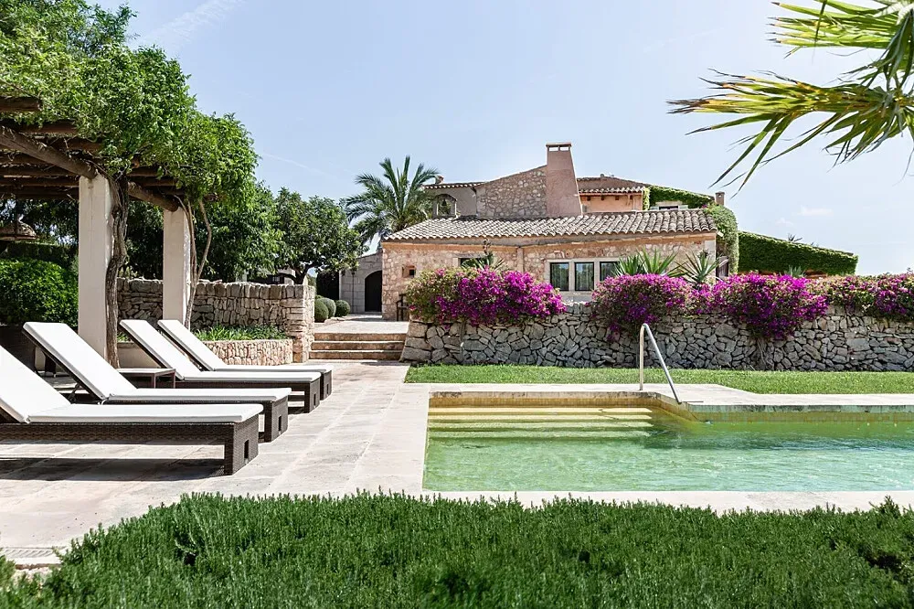 Mallorca Retreats — The retreat is situated in the picturesque countryside of Mallorca, surrounded by gently rolling landscapes. The property itself features a beautiful garden, providing a verdant and peaceful atmosphere for guests to enjoy. A swimming pool offers a refreshing respite during warmer days, complementing the natural beauty of the surroundings.