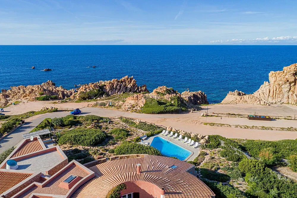 Mira Mare Retreats — Mira Mare Retreats is situated on the North shore of Sardinia, specifically in the Costa Paradiso region. This area is characterized by striking red rock formations that dramatically meet the sea, creating crystal-clear swimming coves like La Sorgente. The atmosphere is one of rugged natural beauty and tranquility, offering a secluded feel despite the stunning coastal vistas.