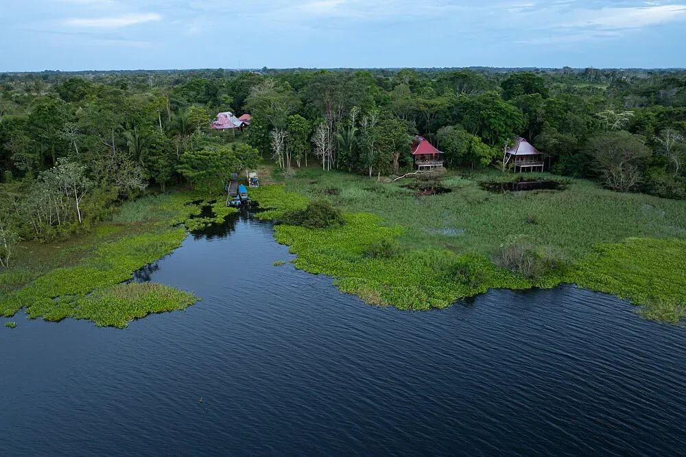Peruvian Camp — The retreat is set deep in the Peruvian Amazon, within a remote village surrounded by pristine rainforest. The atmosphere is one of profound natural immersion, with the jungle's sounds forming a constant, peaceful backdrop. The location is deliberately free from modern distractions, fostering a deep connection to the land.