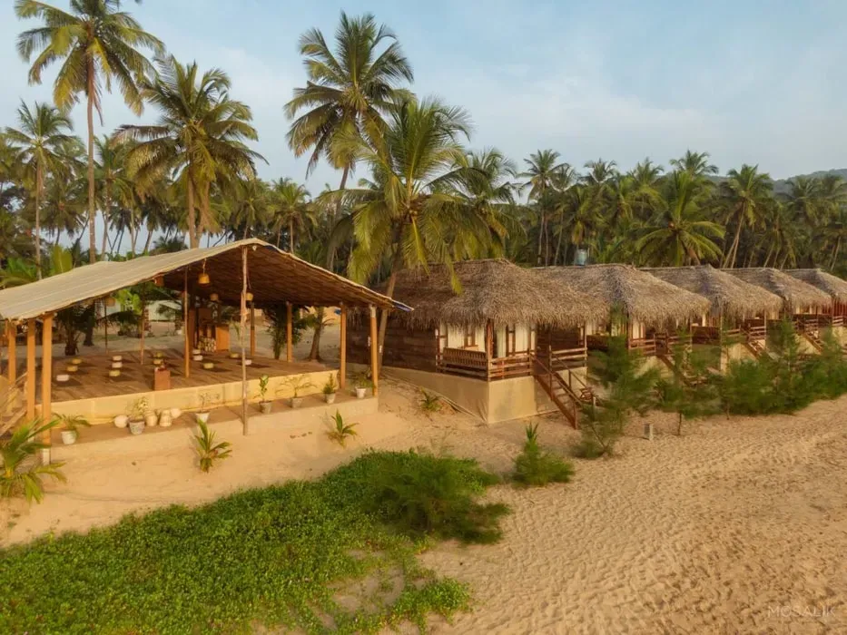 Ravi Yoga — Situated on the peaceful Polem Beach, Ravi Yoga is surrounded by the natural beauty of South Goa, offering expansive views of the Arabian Sea. The atmosphere is one of serene coastal tranquility, with coconut trees providing shade and the gentle sounds of the ocean setting a calming backdrop.