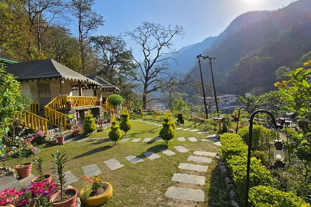 Sahaja Retreat — Sahaja Retreat is nestled on the banks of the River Huel, a tributary of the Ganges, enveloped by a vibrant jungle landscape. It's bordered on both sides by Rajaji National Park, creating an incredibly rich natural environment. The atmosphere is one of serene wilderness, with the constant sound of the river and abundant birdlife.