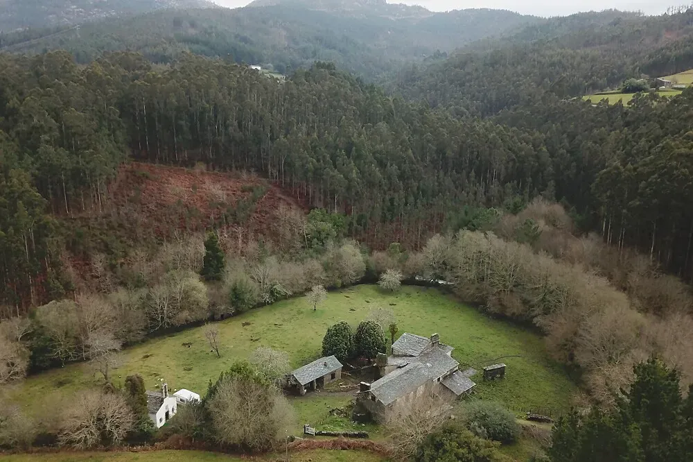 The Foundry — The Foundry is set within a silent valley in rural Galicia, Spain, alongside the powerful Bravos stream. The atmosphere is one of rustic charm and natural tranquility, with the sounds of the stream and the occasional clang from the active blacksmith workshop creating a unique backdrop.
