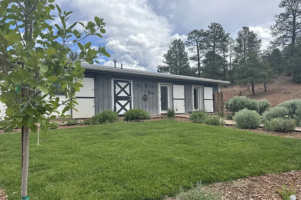 The Healing Barn Retreat Center — Perched on the ridge of the Sangre de Christo mountain range, within the expansive Pecos Wilderness, the center is surrounded by rugged natural beauty. The atmosphere is one of profound tranquility and connection to the high desert landscape, with clear skies and crisp mountain air.