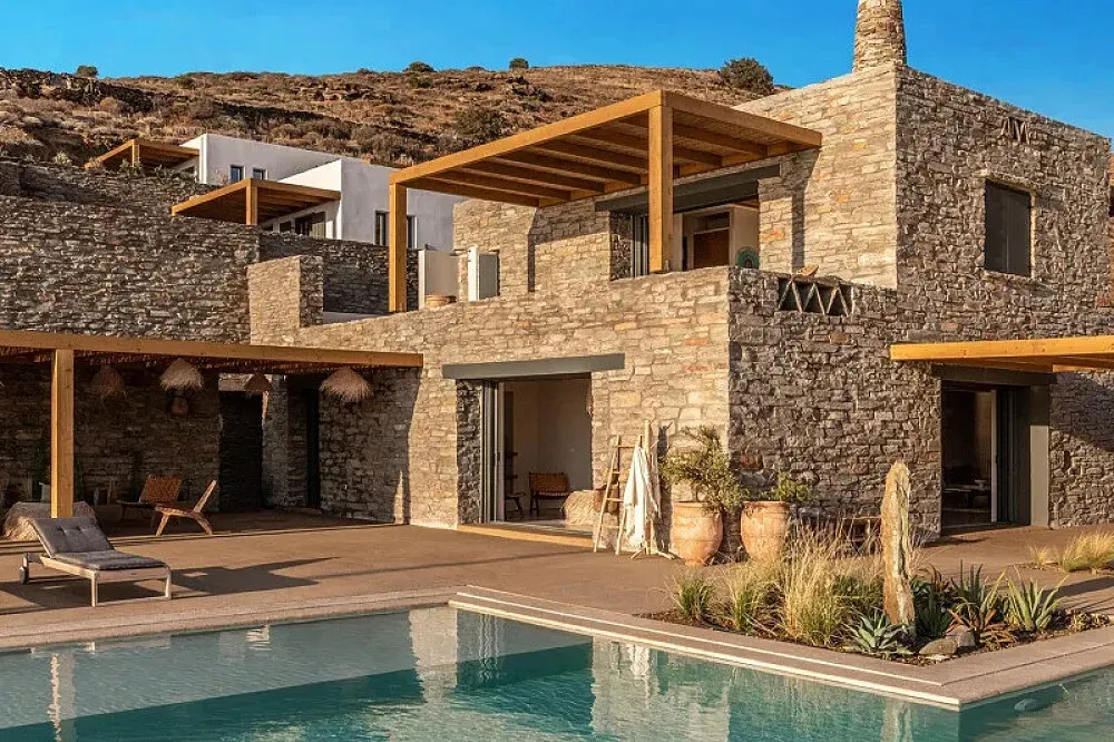 Villa Naos — Perched on the sun-drenched hills of Koundouros, Villa Naos seamlessly blends into its breathtaking natural surroundings. The setting offers sweeping views of the Aegean Sea, with expansive terraces designed for enjoying the island's serene beauty and an infinity pool that merges with the endless blue horizon.