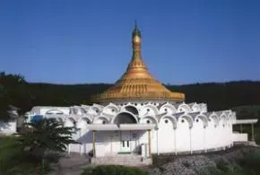 Dhamm Ālaya — The center is situated on 22 acres within a State Park Zone, providing a tranquil and natural environment. Visitors can enjoy views of distant blue hills and lush green fields, accompanied by the sounds of peacocks and other local birdlife, fostering a deep connection with nature during their retreat.