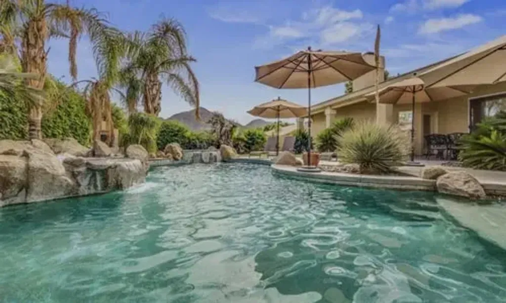 Kyla Mitsunaga — This retreat unfolds in a spacious, 3,600 sq. ft. La Quinta vacation rental in Palm Springs, California. The property boasts an expansive backyard featuring a large private pool, a pool spa, and an inviting outdoor fireplace, well suited to relaxation and reflection under the desert sky. Inside, soaring ceilings, an open floor plan, and walls of glass create a bright and welcoming atmosphere, complemented by a separate media area for comfort.