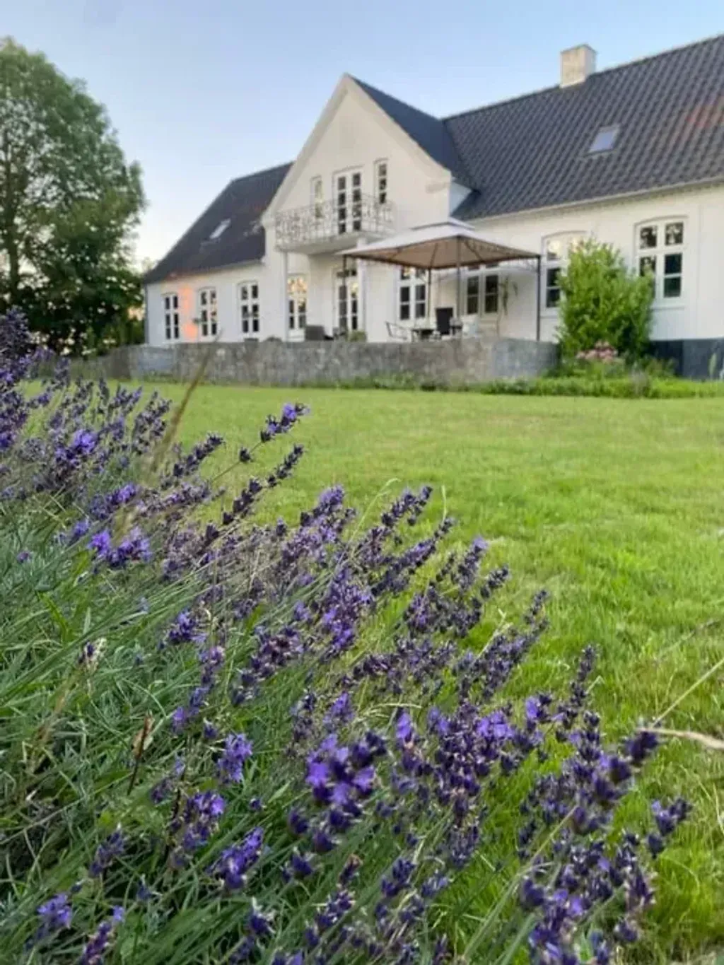 Magic Triangle — The retreat location is set in the open fields of Southern Zealand, surrounded by nature. The property features a large garden, offering ample space to relax and connect with the outdoors. Inside, three cozy living rooms, each with a fireplace, provide comfortable areas for guests.