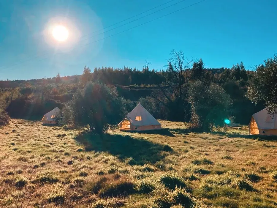 Naturalma — Naturalma is situated in its own private valley, 'Vale da Cerejeiras' (valley of the cherry trees), a remarkably peaceful location in rural Portugal. The venue, known as The Hide, encompasses five acres adorned with olive trees, vibrant greenery, and abundant wildlife. The landscape features rolling hills, forests ripe for exploration, and a refreshing river, all contributing to an atmosphere deeply attuned to nature.