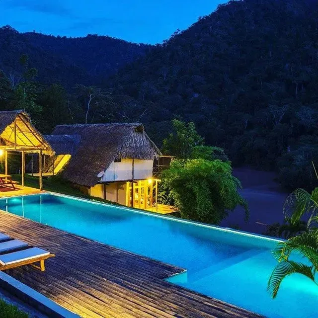 Spring Washam — The retreat is set within the lush, vibrant landscape of the Peruvian Amazon, specifically in Tarapoto. Guests are accommodated at the PumaRinri Amazon Lodge, which boasts stunning views of the river and surrounding mountains. The atmosphere is one of natural tranquility, with a swimming pool and beautiful natural surroundings inviting relaxation and contemplation.