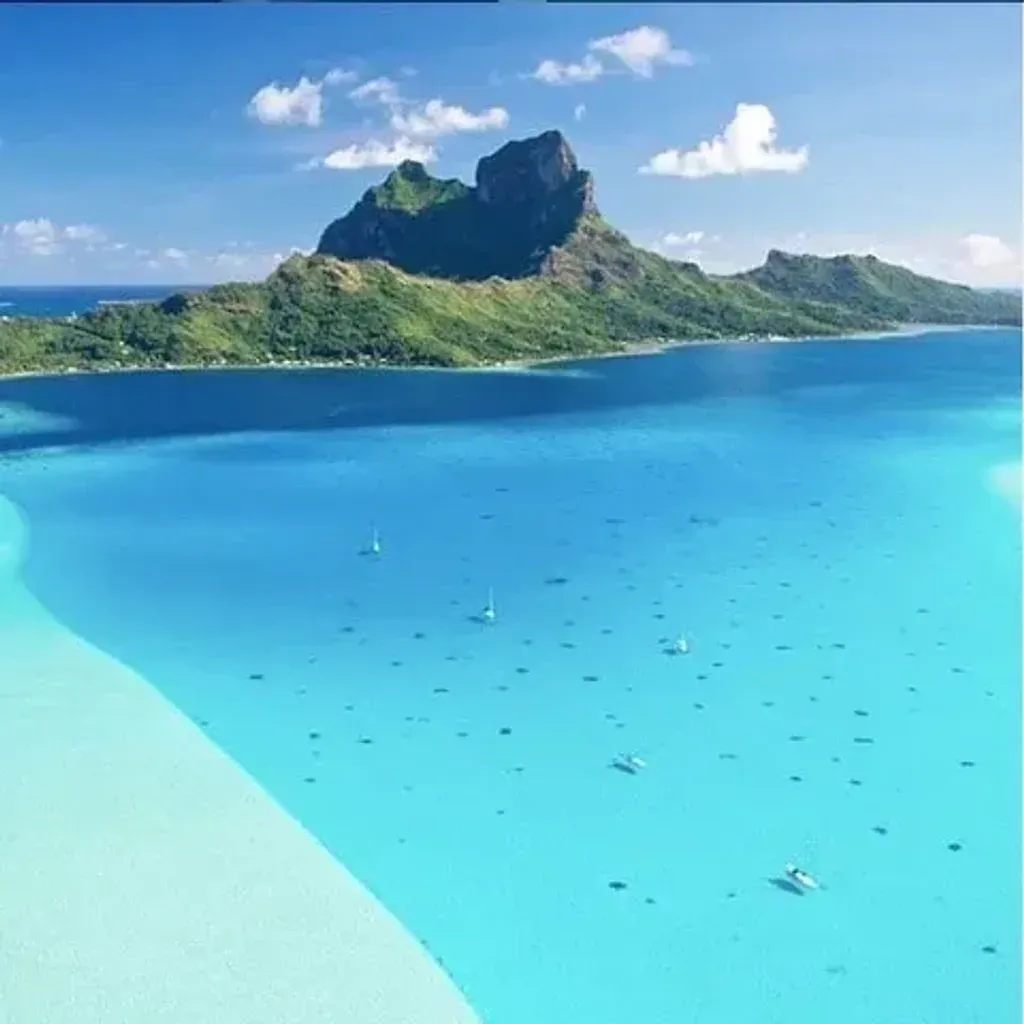 Te Mana Travels — The setting is the idyllic French Polynesian archipelago, specifically the islands of Huahine, Raiatea, and Tahaa. Expect crystal-clear turquoise waters, lush green landscapes, and the gentle rhythm of island life. The experience is split between a charming boutique hotel and the open sea aboard a luxury catamaran, offering diverse perspectives of this tropical paradise.